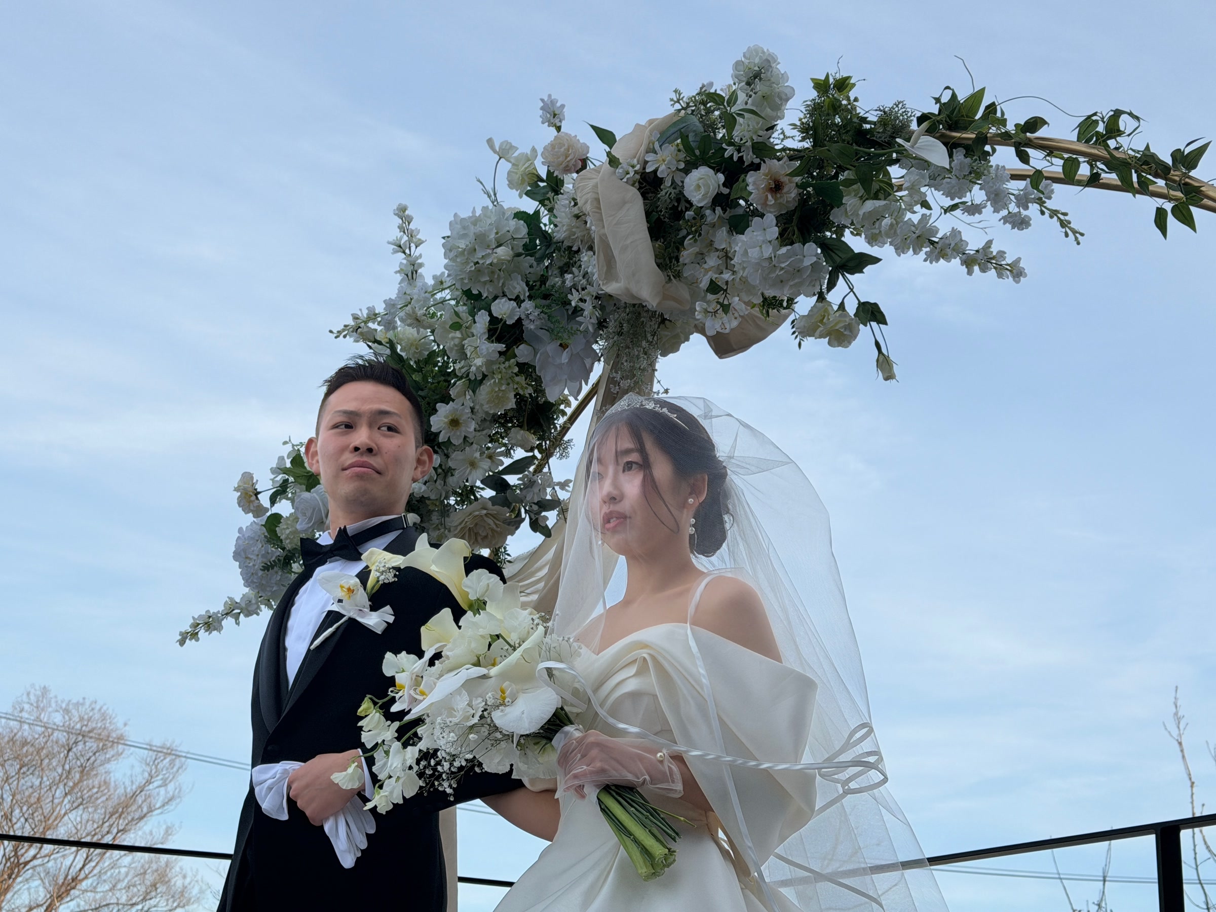 フラワーアーチの前に立つ新郎新婦